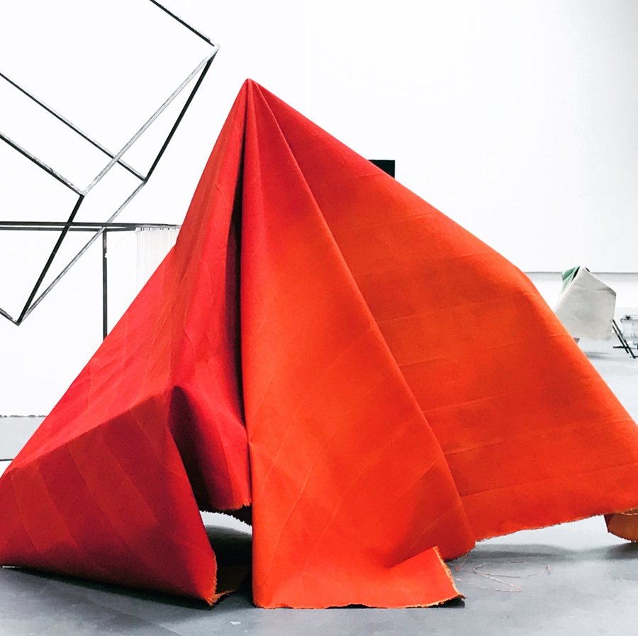 Large vermilion canvas folded into a free-standing tent-like structure on a gallery floor. Canvas Structure, 2019, by Emma Hurst.