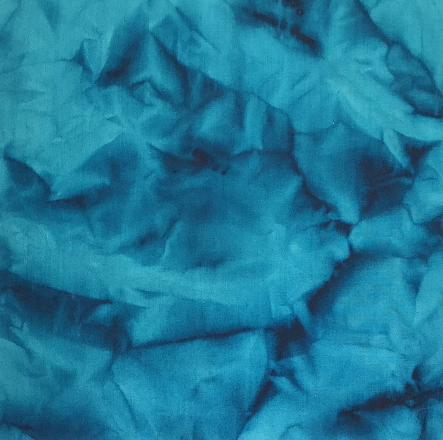 Turquoise linen crumpled and stained, dark pigment gathered in the creases like a map of the folds. Erasure No.3, 2022 by Emma Hurst.