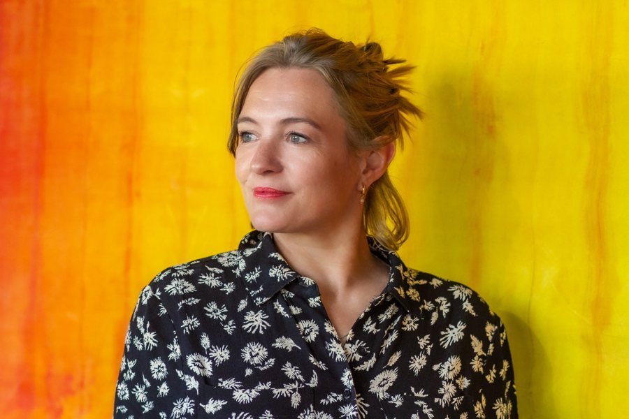 Emma Hurst in front of one of her yellow and orange paintings.