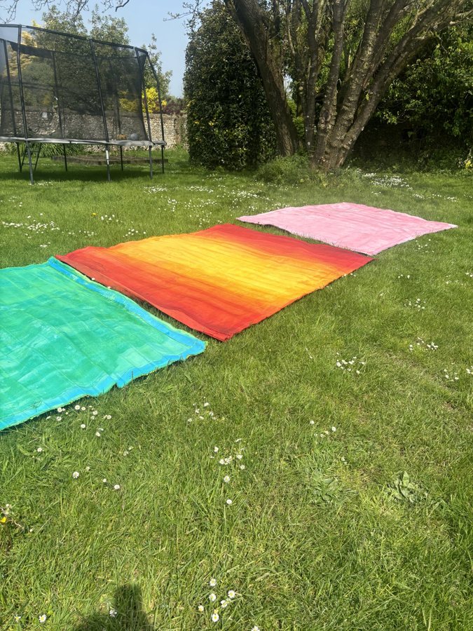 Freshly stained canvases laid out to dry on grass, 2024. Studio process of Emma Hurst.