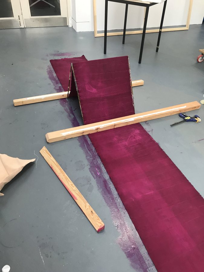 Folded canvas compressed under timber planks on the studio floor, 2019. Studio process of Emma Hurst.