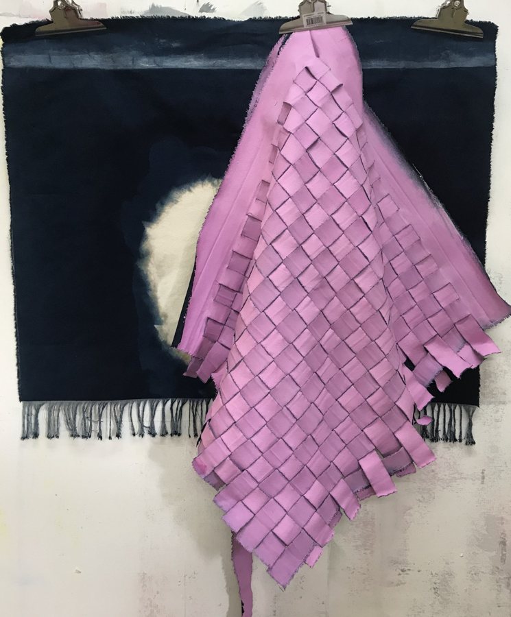 Strips of lilac-pink canvas woven into a loose lattice, draped over a fringed navy panel. Untitled, 2020, by Emma Hurst.