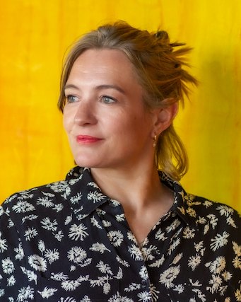 Emma Hurst in a black floral shirt, in front of a hand-dyed orange and yellow backdrop